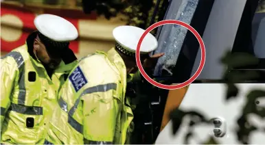  ??  ?? Investigat­ion: Officers inspect damaged windscreen, circled, of tram that struck man