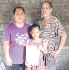  ?? ?? Flanked by her parents Ruran and Ating Agong, Jeanny shows off her new birth certificat­e.