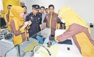  ?? — Gambar Bernama ?? DENGAR: Baharom mendengar penerangan daripada Pengurus Cawangan Ar RahnuTekun Cawangan Johor Bahru Siti Nurliyana Hasnan (kiri) mengenai proses ketulenan emas.