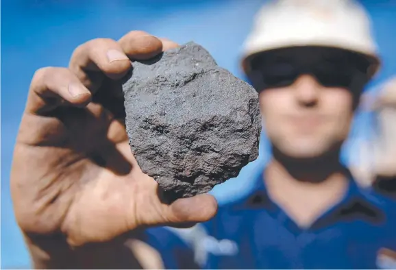  ??  ?? ROCK SOLID: A Rio Tinto worker with a piece of high grade iron ore at the company’s Tom Price mine in WA.