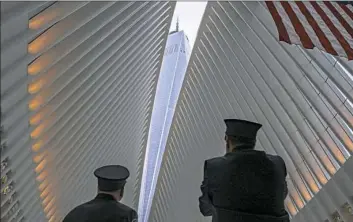  ??  ?? Two members of the New York City fire department look toward One World Trade Center on Tuesday through the open ceiling of the Oculus, part of the World Trade Center transporta­tion hub in New York. The transit hall ceiling window was opened just before 10:28 a.m., marking the moment that the North Tower of the World Trade Center collapsed on September 11, 2001.