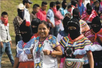  ?? Eduardo Verdugo / Associated Press ?? Masked women escort Maria de Jesus Patricio, presidenti­al candidate for the National Indigenous Congress, as she campaigns in the southern state of Chiapas.