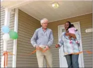  ?? DIGITAL FIRST MEDIA FILE PHOTO ?? Patricia Nnah, holding her 10-week-old daughter, Lukeni, cuts the ribbon on her new home in North Hills with assistance from Gary Lasher, vice president of the board of Habitat for Humanity in Montgomery County.