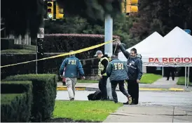  ?? /AFP ?? Search for clues: Members of the FBI survey the area on Sunday outside the Tree of Life Synagogue after a shooting there left 11 people dead in Squirrel Hill, Pittsburgh on Saturday.