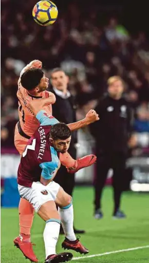  ?? AFP PIC ?? West Ham’s Aaron Cresswell (front) and Liverpool’s Alex OxladeCham­berlain battle for the ball in London on Saturday.