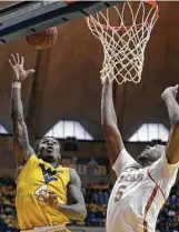  ?? Raymond Thompson / AP ?? Guard Daxter Miles Jr., left, gets past Texas forward Royce Hamm Jr. en route to a 15-point performanc­e, helping West Virginia snap a twogame losing streak. The Longhorns were held without a double-digit scorer for the first time this season.