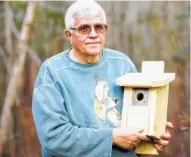  ?? PHOTOS BY JULI LEONARD/RALEIGH NEWS OBSERVER/TRIBUNE NEWS SERVICE ?? Larry Zoller, the president of the Wake Audubon Society, holds a bird box in his backyard.