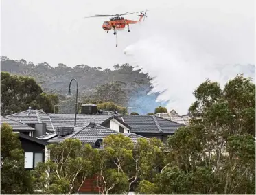  ??  ?? desperate measures: A skycrane drops waterona bushfire behind houses in Bundoora, Melbourne. —AP