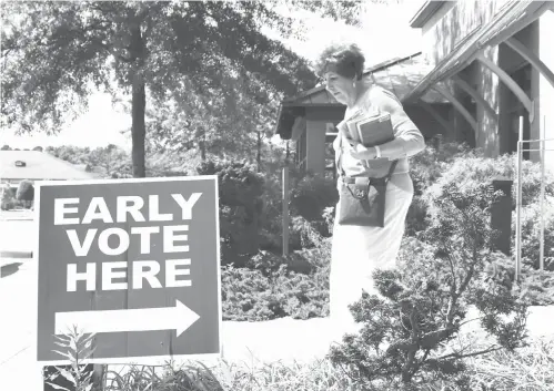  ?? Kelly P. Kissel/Associated Press ?? ■ A library patron passes by a precinct sign outside the Roosevelt Thompson Library on Monday as early voting opened in Little Rock. The May 22 ballot includes Republican and Democratic primaries plus nonpartisa­n judicial elections.