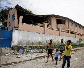  ?? DIEU NALIO CHERY / ASSOCIATED PRESS ?? Residents pass a school Sunday damaged by a magnitude 5.9 quake the night before in Gros-Morne, Haiti. Emergency teams worked to provide relief after the quake killed at least 12 and injured 188.