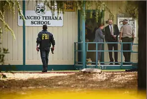  ??  ?? Lockdown: FBI agents going through their investigat­ion outside the Rancho Tehama Elementary School in California. — AFP