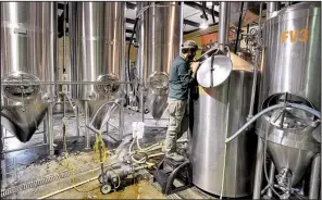  ?? NWA Democrat-Gazette/MICHAEL WOODS ?? Ben Mills, owner of Fossil Cove Brewery in Fayettevil­le, checks the tanks of beer.