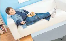  ?? FOTO: IMAGO IMAGES ?? Ein Junge schaut Fernsehen und isst dabei Donuts: Künftig gelten für Werbung für ungesunde Lebensmitt­el Einschränk­ungen.