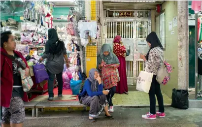  ?? AFP ?? Indonesian domestic helpers use their phones outside a residentia­l building in Hong Kong on Sunday, their day off.—