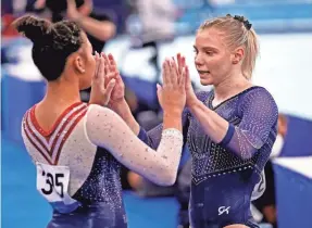  ?? DANIELLE PARHIZKARA­N/USA TODAY SPORTS ?? Jade Carey (USA) high-fives Sunisa Lee (USA) after competing on the balance beam July 29 during the Tokyo 2020 Olympic Summer Games at Ariake Gymnastics Center.