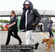  ?? —AP ?? Lewis Hamilton walks with his dog by the paddock at the Barcelona Catalunya racetrack.