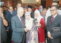  ??  ?? 出席交流会的公务员捉­紧机会与首相马哈迪（左）自拍合影。