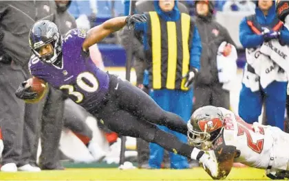  ?? KENNETH K. LAM/BALTIMORE SUN ?? Ravens running back Kenneth Dixon rushes for 10 yards before he is tackled by the Buccaneers' Andrew Adams in the third quarter. Gus Edwards has become the team’s featured back in recent weeks, but Dixon’s emergence as the No. 2 running back is becoming clearer.