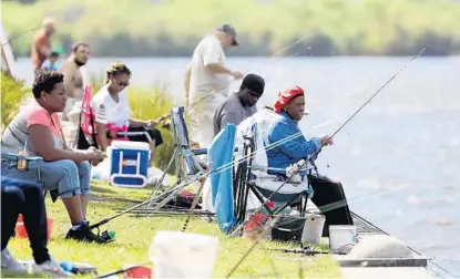  ?? STEPHEN M. DOWELL/ORLANDO SENTINEL ?? Anglers gather to enjoy the afternoon sunshine on Lake Monroe at Sanford’s Riverwalk on Wednesday. Seminole County has not yet issued a stay-at-home order to the public. Osceola County announced Wednesday that it would join Orange County by ordering residents to stay home.