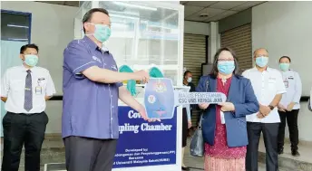  ??  ?? Taufiq presenting the Covid-19 Sampling Chamber to Dr Rundi at Luyang Health Clinic yesterday.