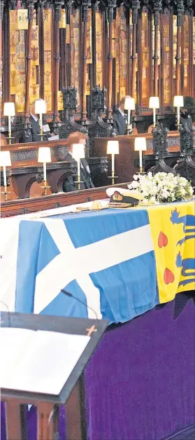  ??  ?? The Queen, on left, looks at Duke’s coffin covered by his personal standard
– a flag representi­ng Denmark, Greece, his surname Mountbatte­n and his title Duke of Edinburgh. Also in row are Prince Andrew, Princess Anne, her husband Sir Timothy Laurence, and Prince Harry