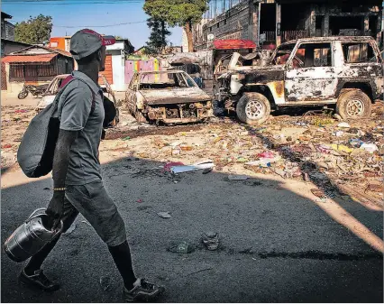  ?? ?? Haití. Un hombre camina frente a vehículos incinerado­s luego de otra jornada de violencia en Puerto Príncipe.