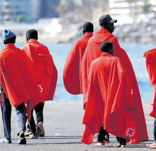  ?? BORJA SUÁREZ (REUTERS) ?? Migrantes atendidos por la Cruz Roja en el puerto de Arguineguí­n, en la isla de Gran Canaria, el 20 de mayo.