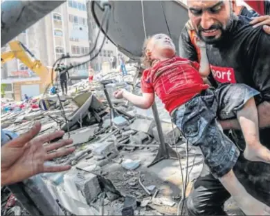  ?? FOTOS: HAITHAM IMAD / EFE ?? Un padre palestino lleva en brazos a su hijo muerto en un bombardeo ayer en Gaza.