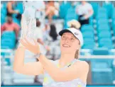  ?? MICHAEL REAVES/GETTY ?? Iga Swiatek raises the Butch Buchholz Trophy after defeating Naomi Osaka in the singles final Saturday in Miami Gardens, Florida.