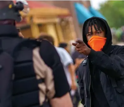  ?? © afp ?? Een betoger in Minneapoli­s gaat in discussie met een agent. Over heel de VS vinden vreedzame, maar ook gewelddadi­ge protesten plaats.