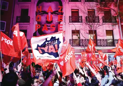  ?? — AFP photo ?? Supporters of ruling Spanish Socialist Party celebrate in front of the party headquarte­rs in Madrid.