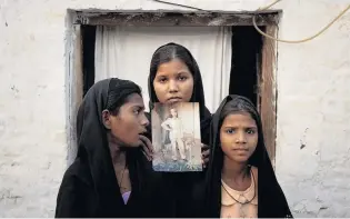  ?? PHOTOS: REUTERS ?? Long time gone . . . Asia Bibi’s daughters pose with an image of their mother in November 2010. Standing left to right are Esha (then 12), Sidra (18) and Eshum (10).