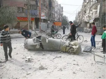 ?? — Reuters ?? People inspect missile remains in the besieged town of Douma, in eastern Ghouta, in Damascus, on Friday.