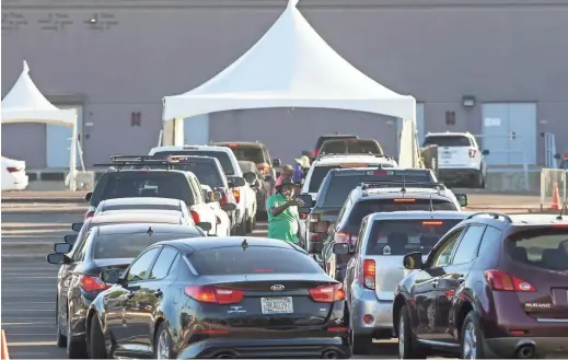  ?? THOMAS HAWTHORNE/THE REPUBLIC ?? Volunteers coordinate vehicles at a drive-thru testing site hosted by the HeroZona Foundation in the South Mountain Community College parking lot in Phoenix on Thursday. Tests were free and vehicles waited in a line that stretched nearly 1.5 miles.