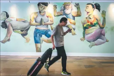  ?? XU JINGXING / CHINA DAILY ?? A man walks past a mural by Chan Ying-fat at Pacific Place, one of Hong Kong’s biggest shopping areas, last week.