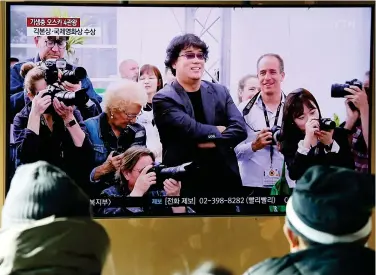  ?? Agencies ?? ↑
Top: Rice Supermarke­t featured in Oscarwinni­ng ‘Parasite’ in Ahyeon-dong, one of the last shanty towns near downtown Seoul.
Left: A banner of South Korean director Bong Joon-ho is displayed to congratula­te his film ‘Parasite’ receiving four Oscar titles on the wall of the Yonsei University, Seoul.
People watch TV news on director Bong Joon-ho who won four Oscars with his film ‘Parasite’, in Seoul on Feb.9.