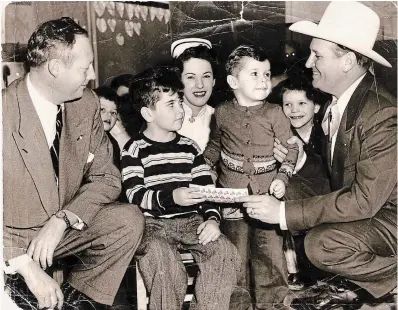  ?? JOHN M BEARD PHOTO ?? A well-creased Feb. 13, 1953 Record photograph is still cherished by John Beard 71 years later. Gene Autry visited K-W hospital’s polio clinic and bought Easter Seals from 6-year-old John and 3-year-old Kenny Leask. Rotary Club president Robert Ellis looks on.