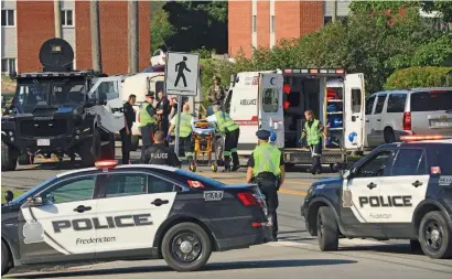  ?? AP ?? police officers and paramedics survey the area of a shooting in Fredericto­n, new Brunswick, canada on Friday. —