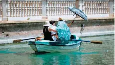  ??  ?? People protect themselves from the sun with umbrellas while they take a boat ride at Parque de Maria Luisa, on a hot summer day in Sevilla, as a heatwave hits Spain and Portugal. — AFP