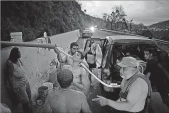  ?? [RAMON ESPINOSA/THE ASSOCIATED PRESS] ?? People affected by Hurricane Maria bathe in and collect water piped from a creek in the mountains in Naranjito, Puerto Rico. A man who lives along the creek set up the pipe to help those left without water after Hurricane Maria.