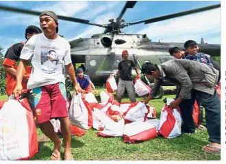  ??  ?? Help arrives: Villagers offloading supplies from a military helicopter at Proo village, Lindu district in Central Sulawesi’s Sigi regency.— AFP