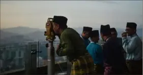  ?? Arif Kartono/AFP via Getty Images ?? An officer of Malaysia’s Islamic authority uses a theodolite to perform rukyah — the sighting of the new moon to mark the start of Islam’s holy month of Ramadan — at the KL Tower in Kuala Lumpur on Sunday.