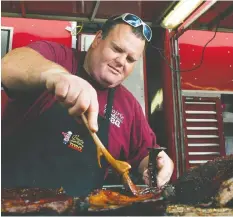  ?? JENELLE SCHNEIDER/PNG FILES ?? Rob Reinhardt of Prairie Smoke and Spice fires up some ribs at the PNE Fair in 2014. The Reinhardts are participat­ing in the Car-B-Q.