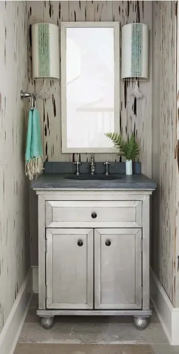  ??  ?? |LEFT| MODERN JUXTAPOSIT­ION. The textured wallpaper in this bathroom is reminiscen­t of driftwood, while a chrome vanity brings a modern touch to the beachy space.
|OPPOSITE BOTTOM| SHIP-SHAPE SHIPLAP. Beachy textures abound in this bedroom, where a...