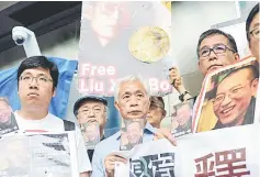  ??  ?? Protesters prepare to post postcards written and addressed to Liu (pictured on cards) outside the General Post Office in Hong Kong. — AFP photo