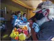  ?? ANDA CHU — STAFF PHOTOGRAPH­ER ?? Morris Giguiere picks up meals to go from Martha’s Kitchen volunteers Sigrid Roemer, left, and her husband, Bruce Factor, center, at Sacred Heart of Jesus Parish hall Oct. 21.