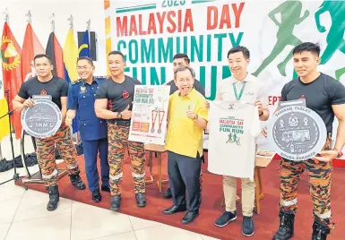  ?? ?? AKTIVITI SIHAT: Dr Sim (tiga kanan) bersama Eijing (dua kanan) dan Khirudin (dua kiri) menunjukka­n kemeja, poster dan replika pingat larian amal Malaysia Day Community Fun Run 2023 di Farley Batu 6, Kuching semalam.