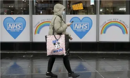  ?? Photograph: Kirsty Wiggleswor­th/AP ?? ‘If anything, adherence to social distancing, mask wearing and hygiene measures is higher than ever.’ A woman in London walks past signs to support the NHS.