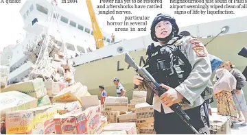  ?? — Reuters photo ?? A policeman stands as he secures the transfer of food and aid for victims following a quake and tsunami at Pantoloan port in Palu in this photo taken by Antara Foto.