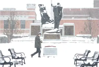  ?? JASON BAIN/EXAMINER ?? A man walks by the Book of Remembranc­e in a snowy Confederat­ion Square on Monday. A White Christmas in the Peterborou­gh area is a near certainty.